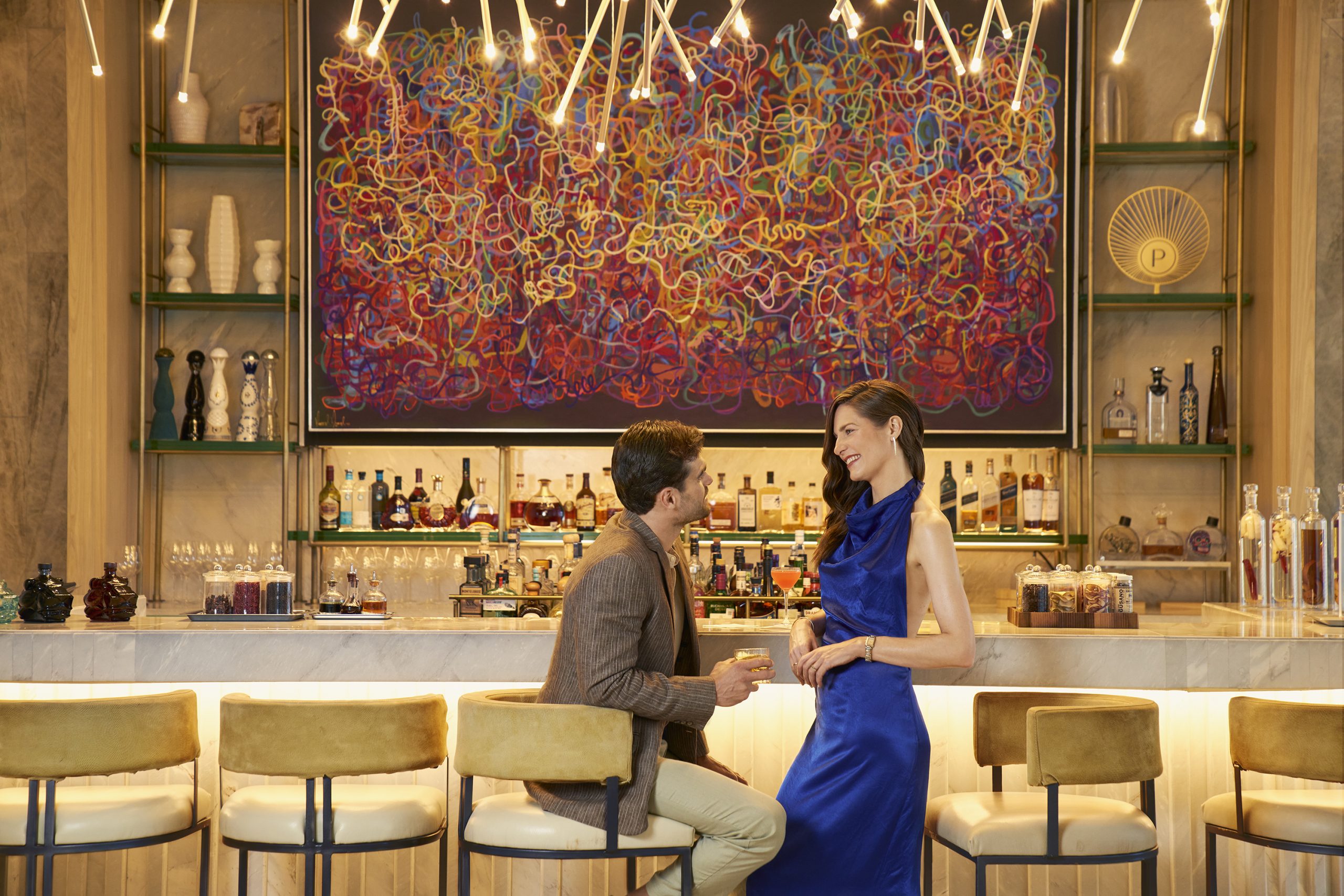 A smiling couple stands, happily talking to each other at the bar.