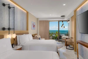 Bright suite with two beds, private balcony, and ocean view