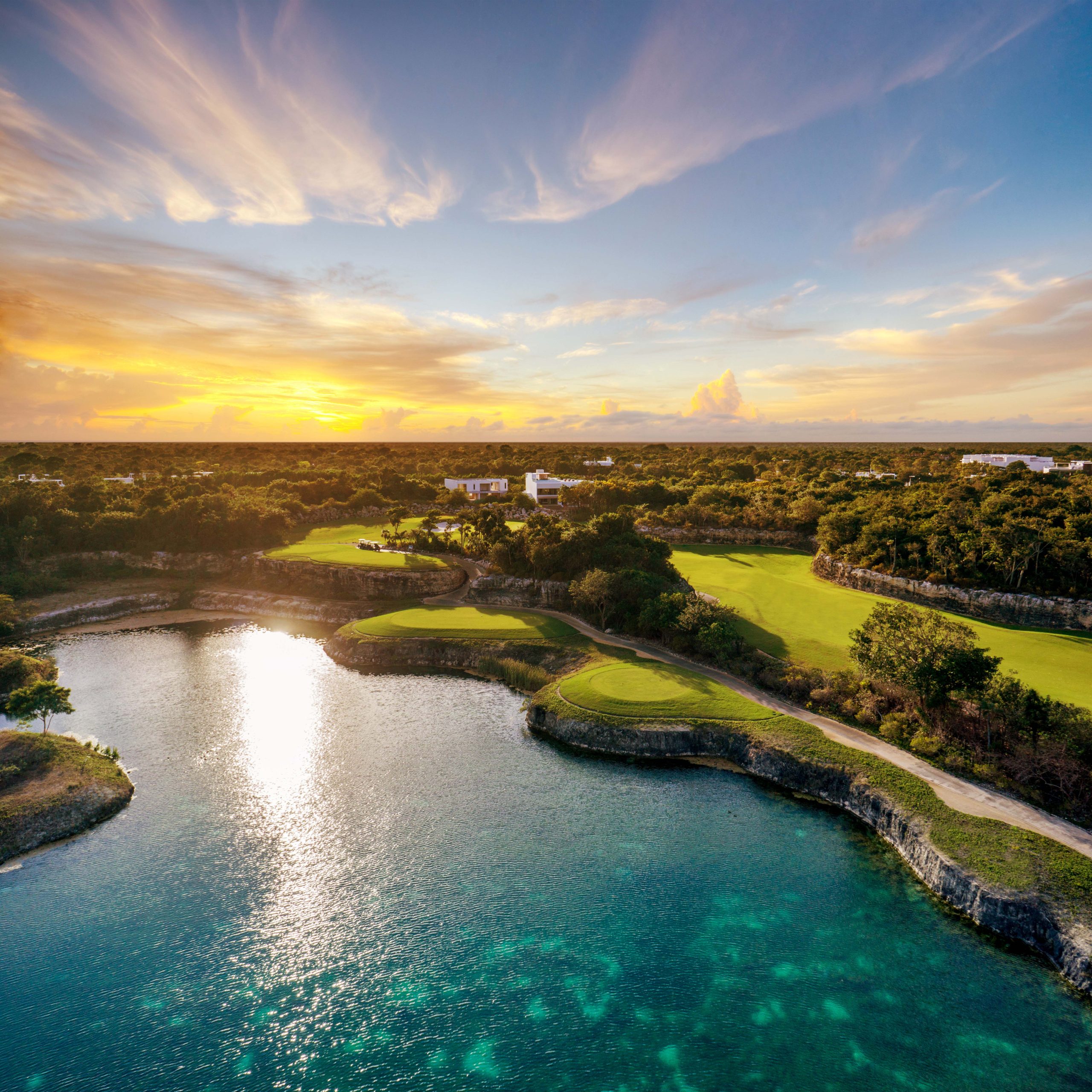 Aerial photo of a lake surrounded by lush, vibrant green landscape.