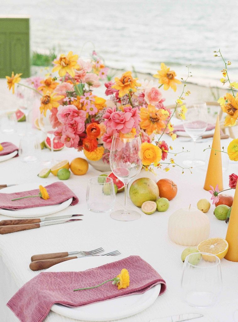 Una mesa de comedor junto al mar decorada con vajilla y flores, que ofrece unas impresionantes vistas del océano.