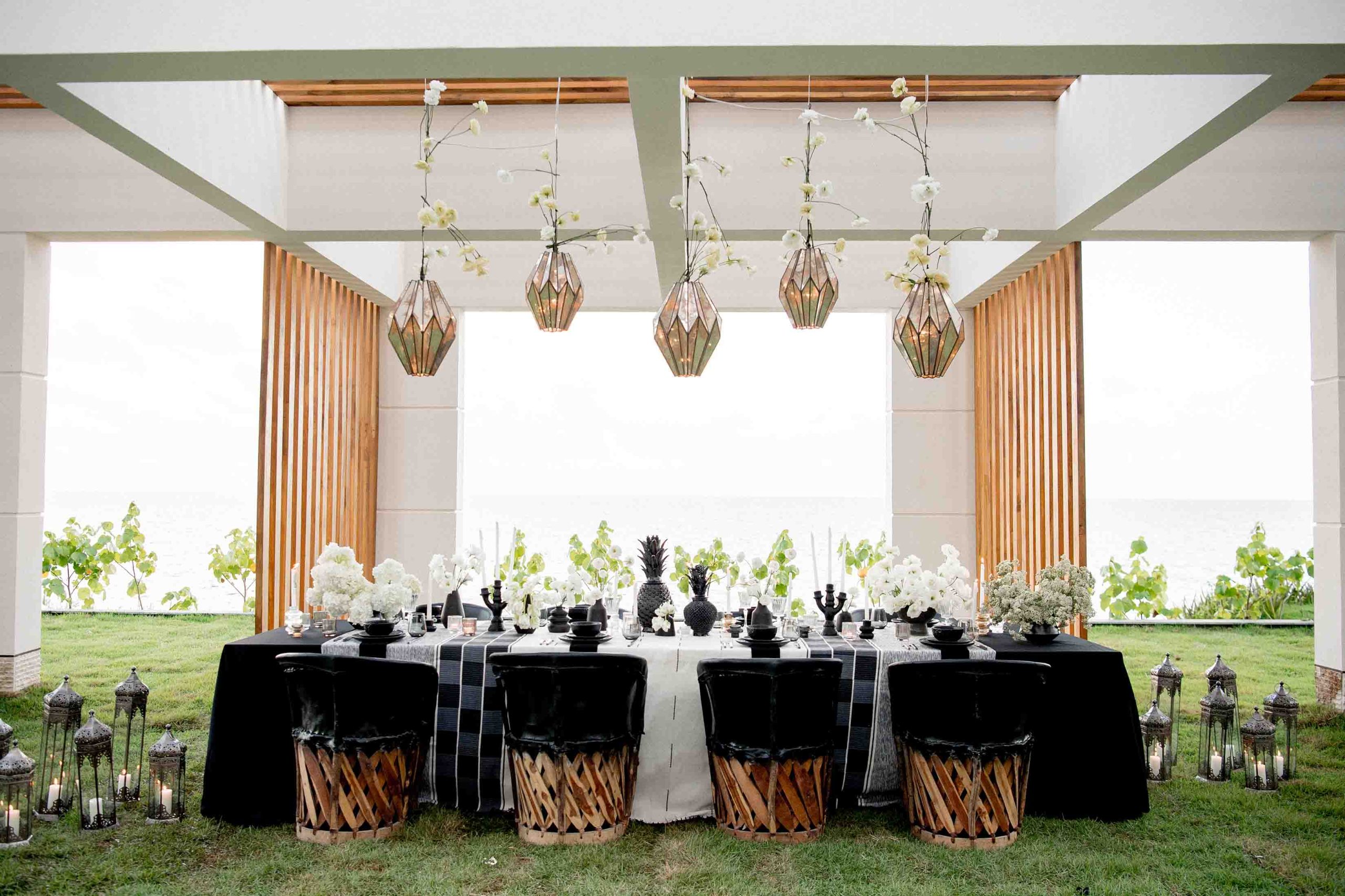 A fully decorated dining table blends elegance with nature, offering a stunning ocean view.
