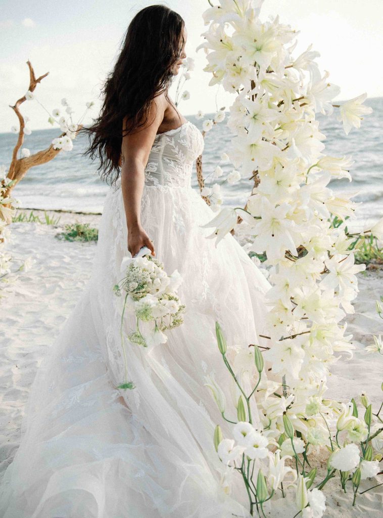 Una dama vestida de blanco se alza con gracia ante la elegante decoración nupcial.