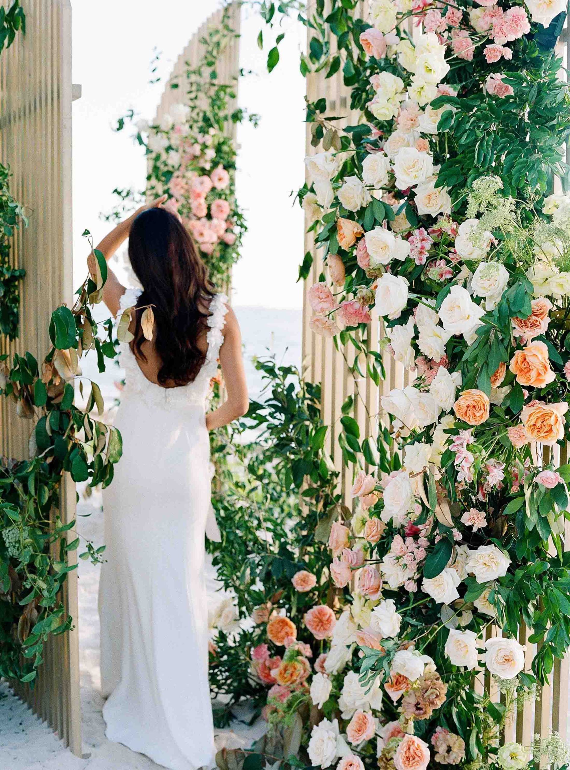 Una dama vestida de blanco se alza con elegancia ante la decoración de la boda.