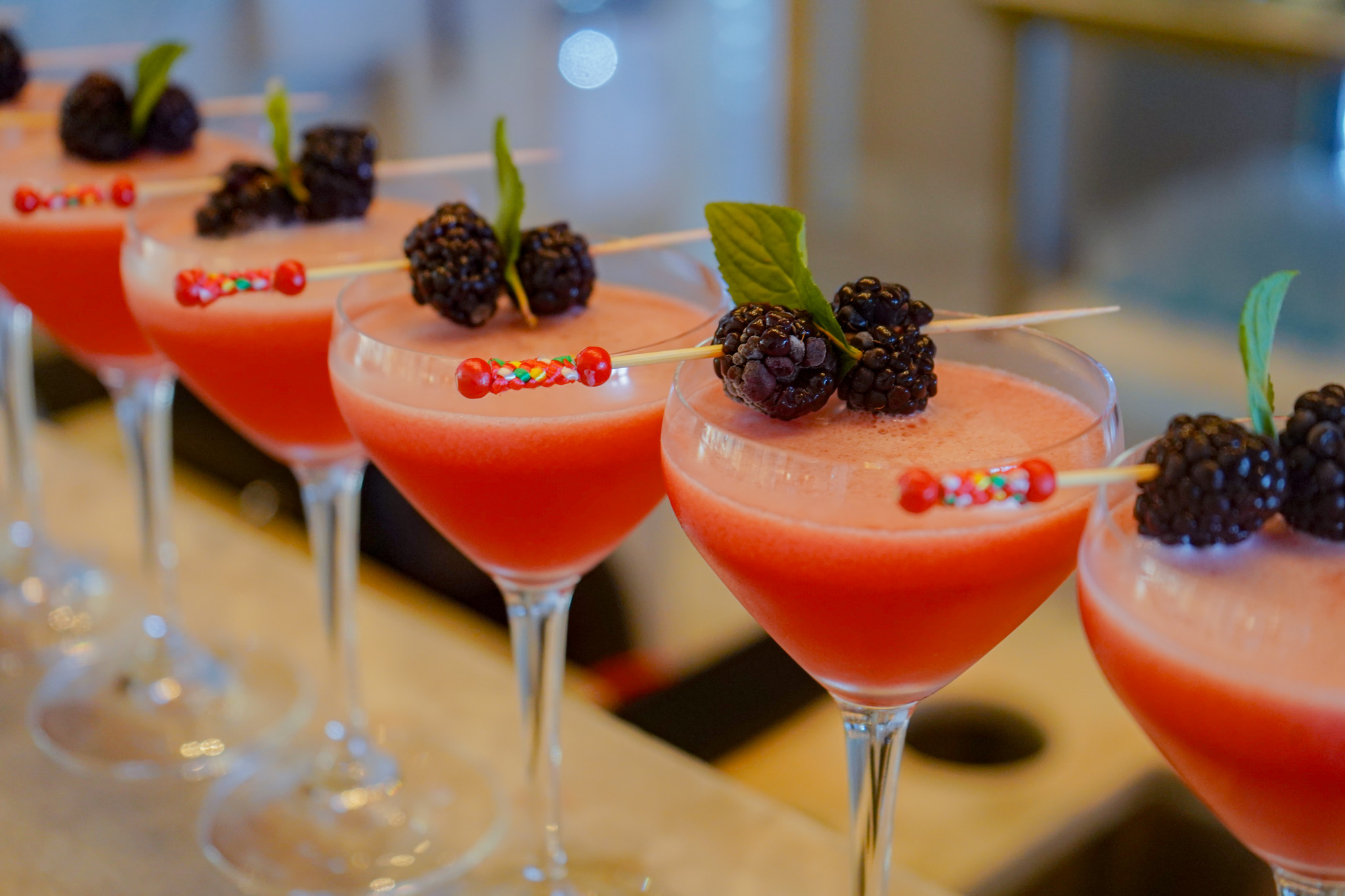 Many cocktail glasses are elegantly arranged on the polished bar counter table.