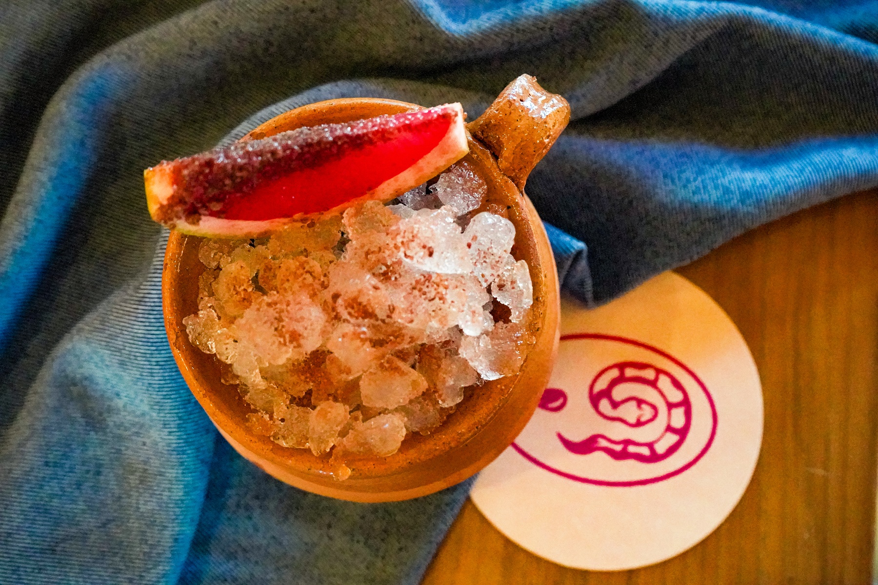 A cocktail glass filled with shaved ice is beautifully garnished with fresh, colorful fruit pieces.