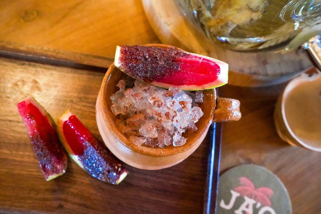 A cocktail glass with shaved ice is garnished with fresh, colorful fruit pieces.