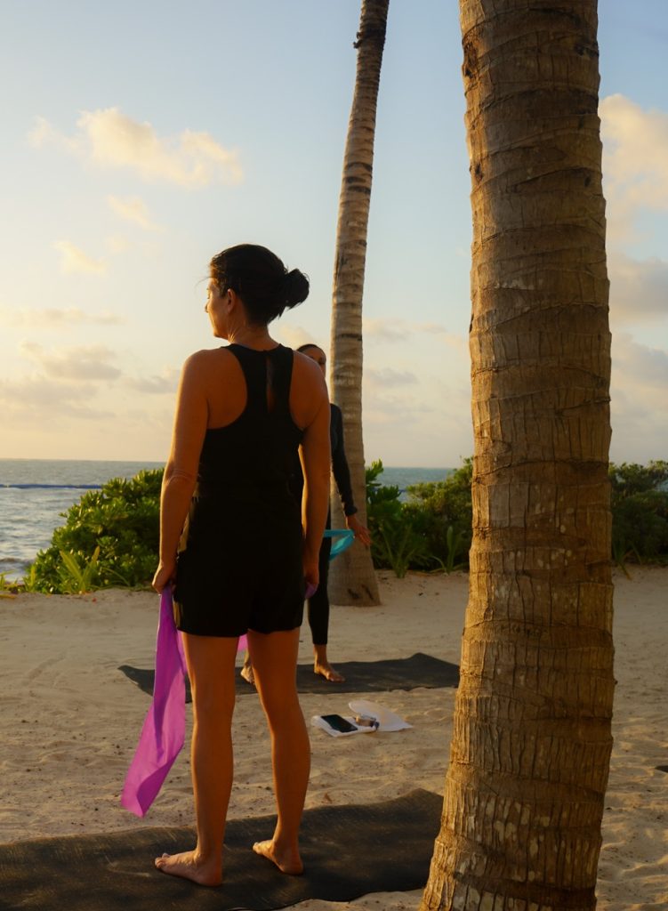 A lady is practicing yoga gracefully on the peaceful, sandy beach at sunrise.